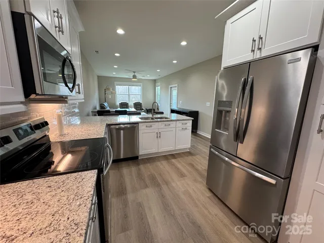 a kitchen with stainless steel appliances granite countertop a refrigerator a stove a sink and a microwave