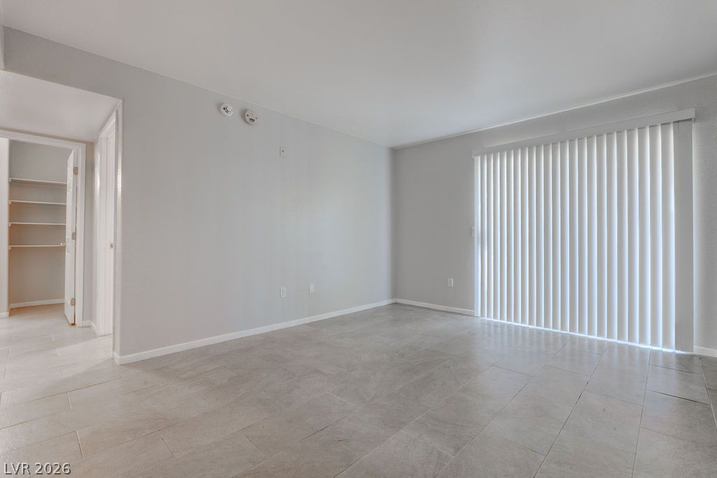 7885 West Flamingo Road, Unit 1016 Las Vegas, NV 89147 - Photo 2 of 24 A spacious room offers tile flooring and vertical blinds for privacy.