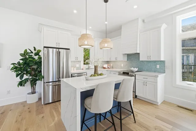 a kitchen with stainless steel appliances granite countertop a refrigerator a sink dishwasher a refrigerator a oven a stove and white cabinets with wooden floor