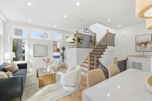 a living room with couches and kitchen view with wooden floor