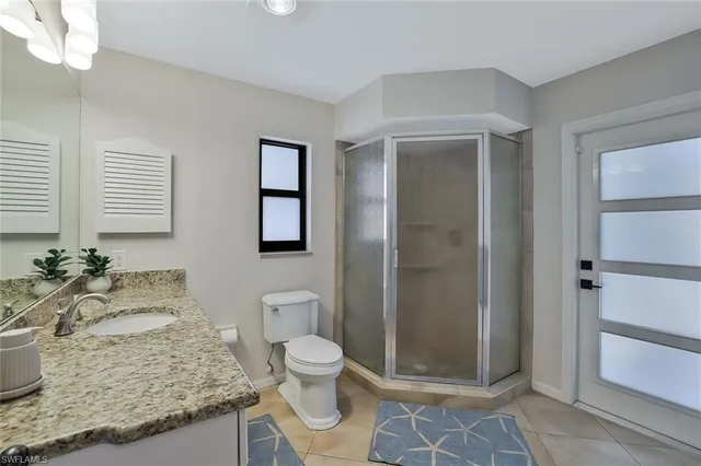 a bathroom with a granite countertop sink a toilet and shower