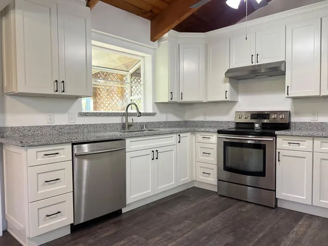 a kitchen with a refrigerator a sink and dishwasher with wooden floor