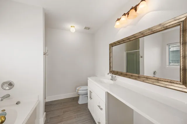 a bathroom with a granite countertop sink a toilet and a mirror