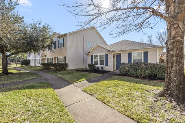 a view of a white house with a large tree and plants