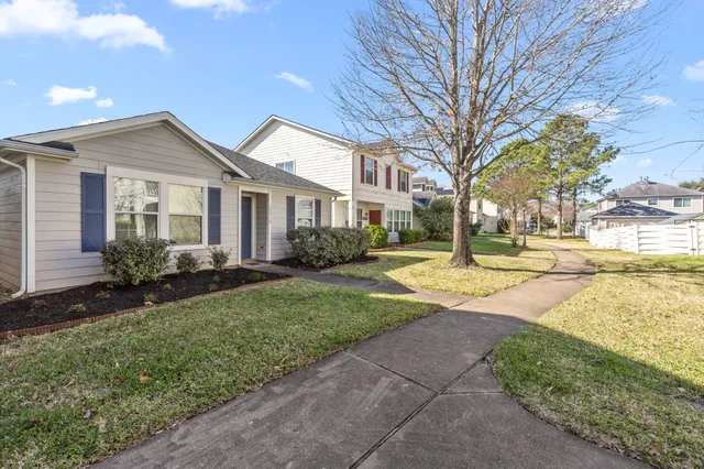 a view of a yard in front of a brick house with many windows