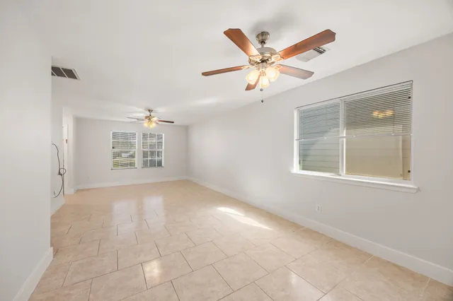 an empty room with windows and fan