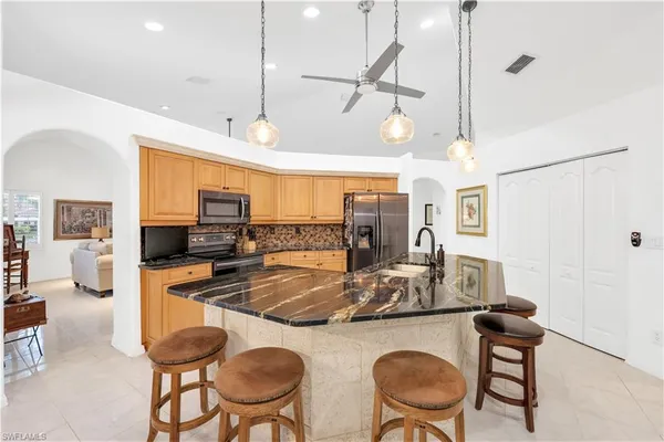 a kitchen with stainless steel appliances kitchen island granite countertop a table chairs and a refrigerator