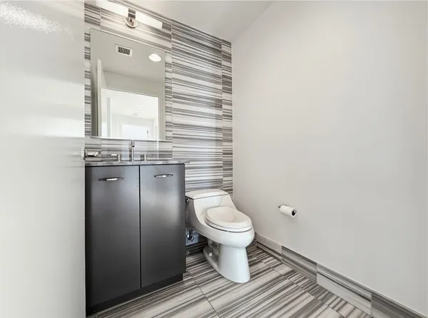 a bathroom with a granite countertop toilet and a sink