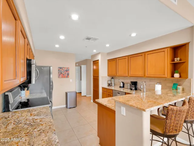 a kitchen with stainless steel appliances kitchen island granite countertop a refrigerator and a sink