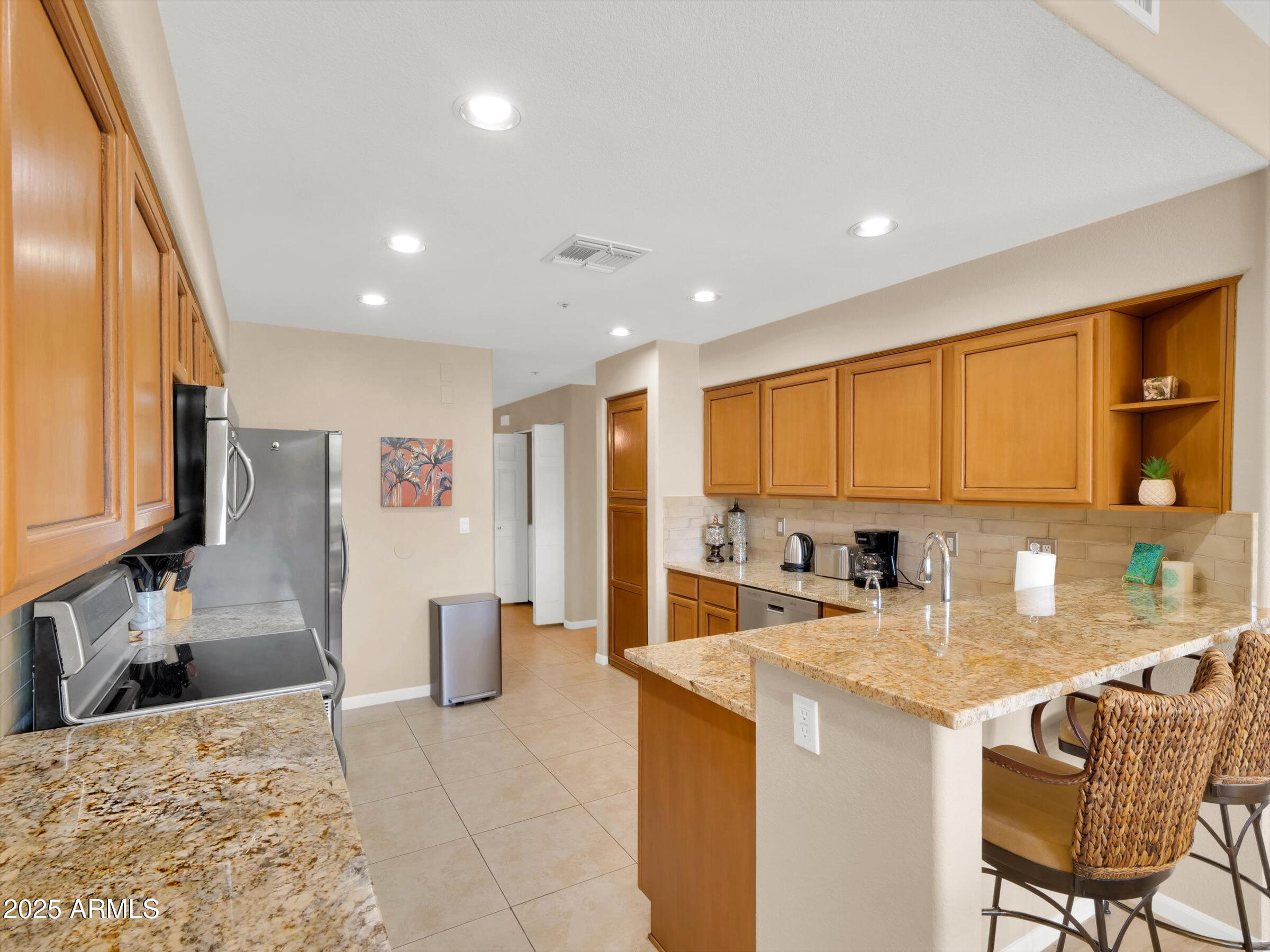 7700 East Gainey Ranch Road, Unit 120 Scottsdale, AZ 85258 - Photo 14 of 57 a kitchen with stainless steel appliances kitchen island granite countertop a refrigerator and a sink