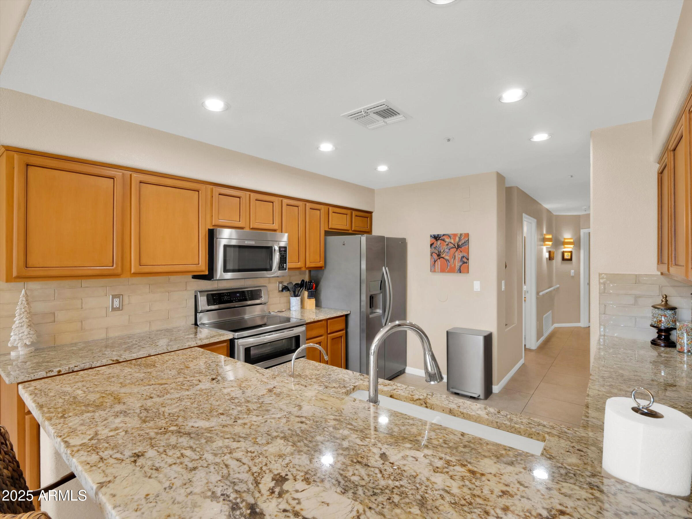 7700 East Gainey Ranch Road, Unit 120 Scottsdale, AZ 85258 - Photo 15 of 57 a kitchen with stainless steel appliances granite countertop a sink refrigerator and microwave