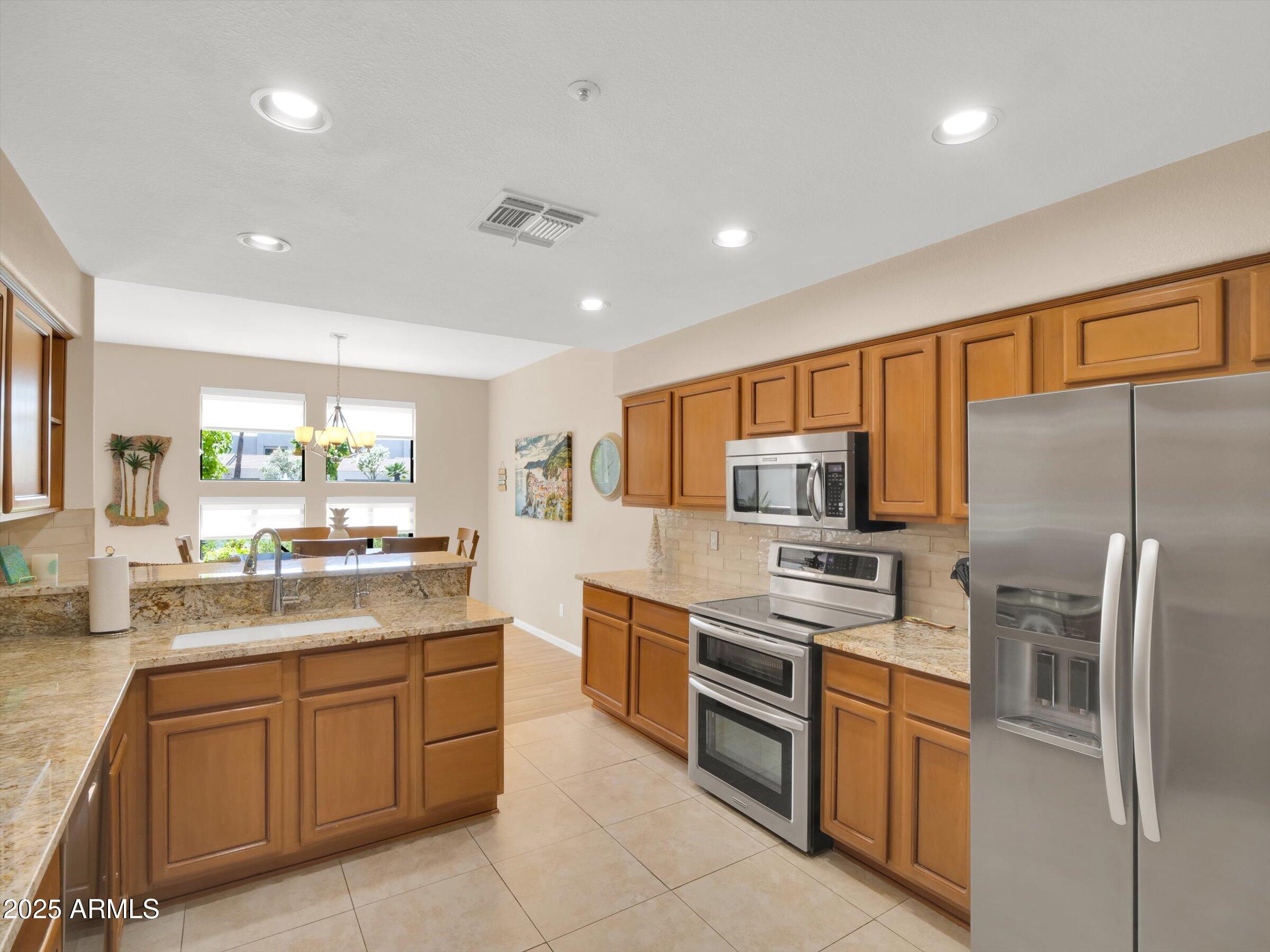 7700 East Gainey Ranch Road, Unit 120 Scottsdale, AZ 85258 - Photo 17 of 57 a kitchen with stainless steel appliances granite countertop refrigerator sink and microwave