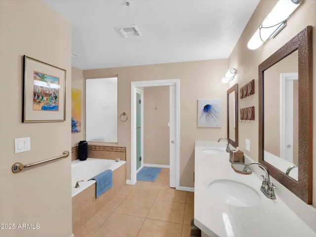 a bath tub sitting next to a white wall and painting on the wall