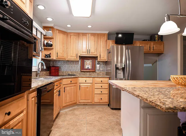 a kitchen with stainless steel appliances granite countertop sink refrigerator and cabinets