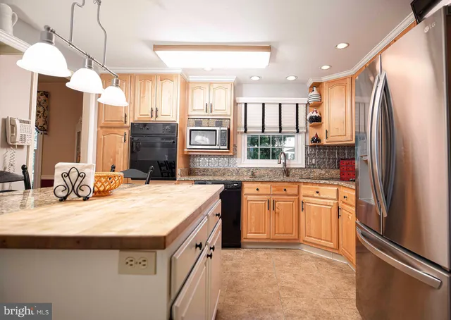 a kitchen with stainless steel appliances granite countertop a refrigerator a sink a stove and oven