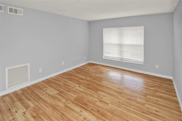 a view of an empty room with wooden floor and a window