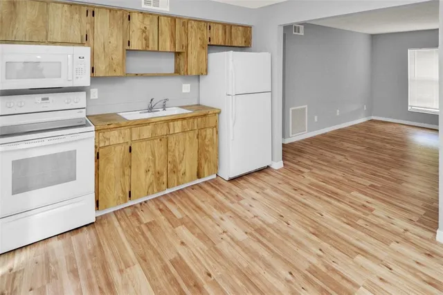 a view of a kitchen with wooden floor and electronic appliances