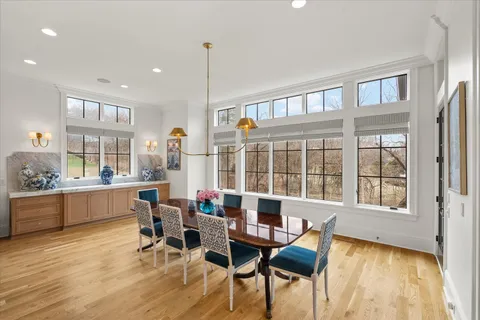 a living room with couches bookshelf and a dining table with wooden floor