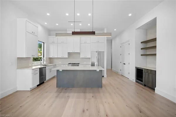 a large kitchen with stainless steel appliances granite countertop a stove a refrigerator a sink and white cabinets