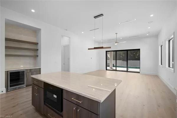 an empty room with wooden floor a ceiling fan and windows