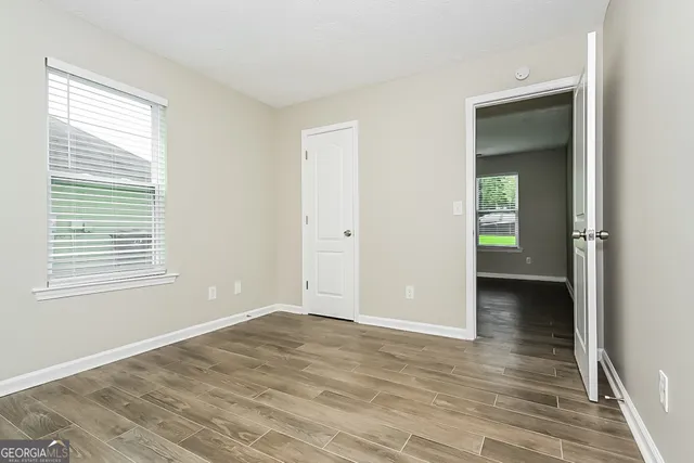 a view of an empty room with wooden floor and a window