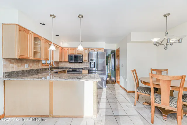 a kitchen with stainless steel appliances kitchen island granite countertop a table chairs and a refrigerator