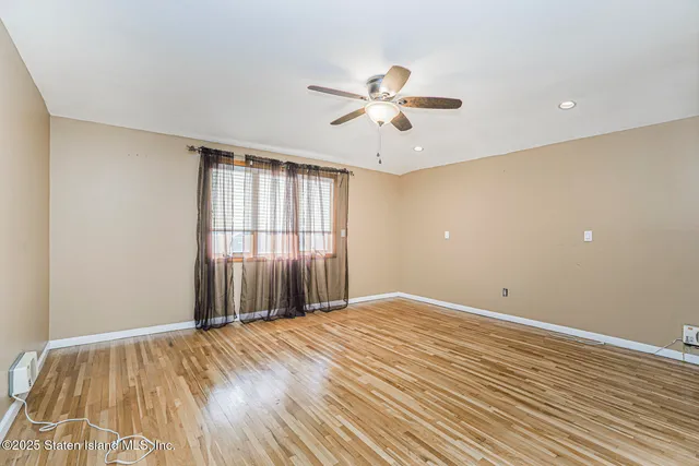 a view of an empty room with window and wooden floor