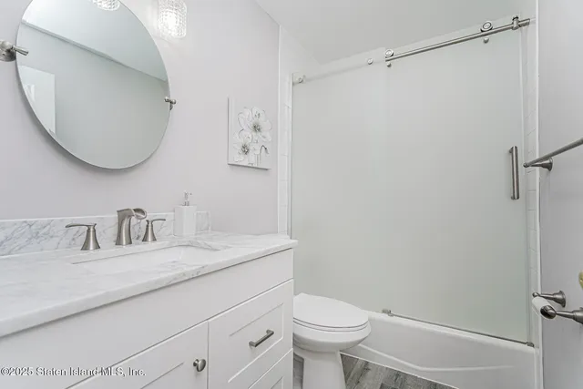 a bathroom with a granite countertop sink mirror vanity and toilet