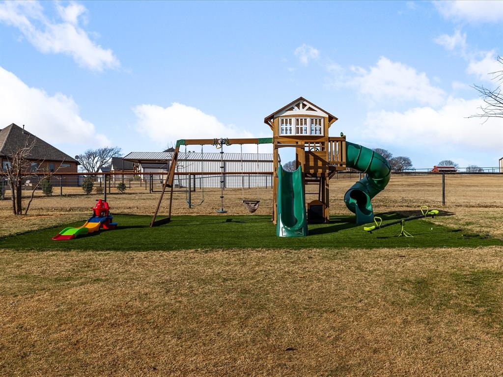 170 Proctor Lane Decatur, TX 76234 - Photo 31 of 34 Outdoor play structure featuring a slide, swings, and a climbing area, set on an artificial turf base