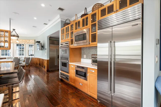 a kitchen with stainless steel appliances a refrigerator and a wooden floor