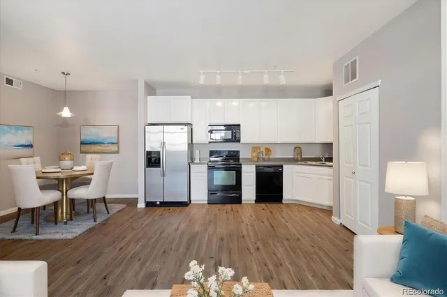 a kitchen with stainless steel appliances wooden floor and a refrigerator