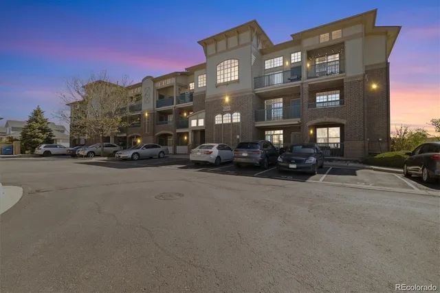 a city street lined with parked cars front of buildings