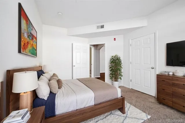a bedroom with a bed and a flat tv screen on dresser