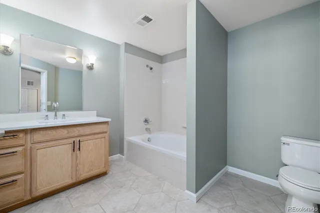 a spacious bathroom with a sink a toilet a mirror and a bathtub