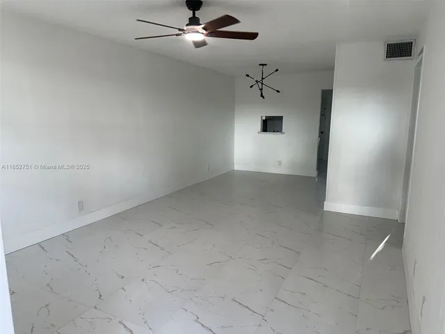 an empty room with a ceiling fan and carpet