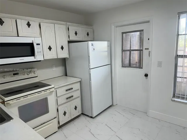 a kitchen with white cabinets and white appliances