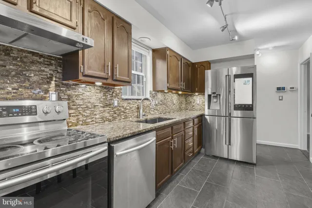 a kitchen with stainless steel appliances granite countertop a sink a stove a refrigerator cabinets and a counter top space