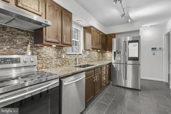 a kitchen with stainless steel appliances granite countertop a sink a stove a refrigerator cabinets and a counter top space