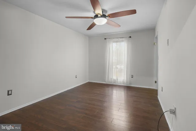 an empty room with wooden floor ceiling fan and windows