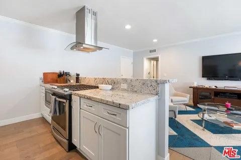 a kitchen with a stove and a flat screen tv