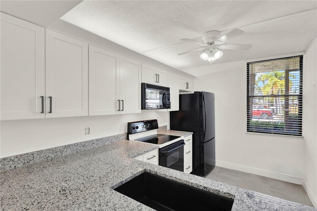 1950 Southwest Palm City Road, Unit 9102 Stuart, FL 34994 - Photo 11 of 51 a kitchen with stainless steel appliances granite countertop a refrigerator stove and sink