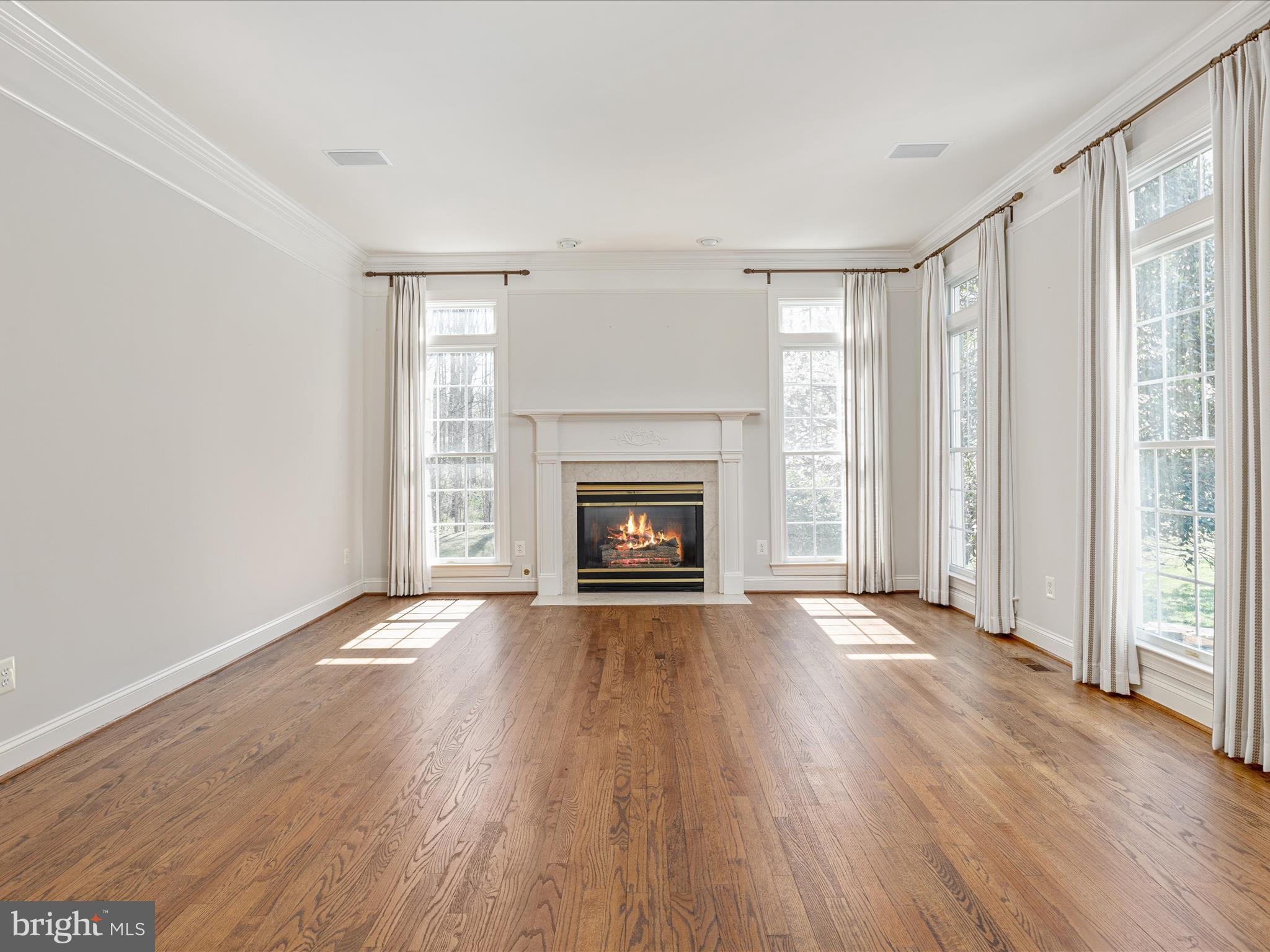 10554 Fox Forest Drive Great Falls, VA 22066 - Photo 3 of 77 an empty room with wooden floor fireplace and windows