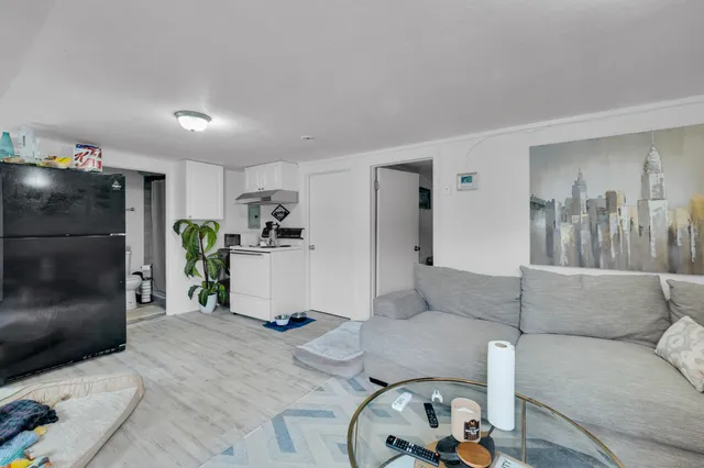 a living room with furniture and a refrigerator