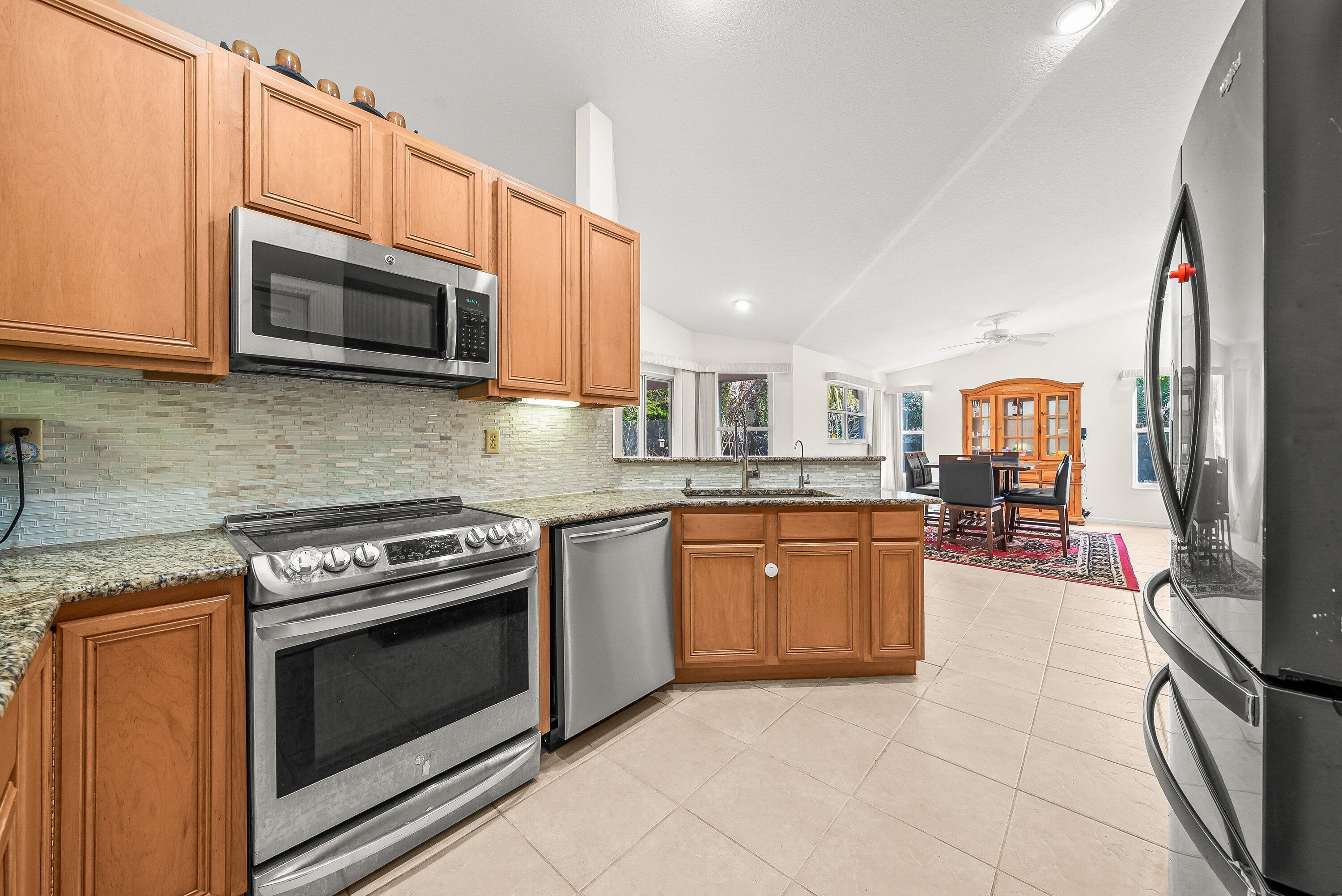 18098 93rd Road North The Acreage, FL 33470 - Photo 15 of 60 a kitchen with stainless steel appliances granite countertop a stove top oven microwave and cabinets