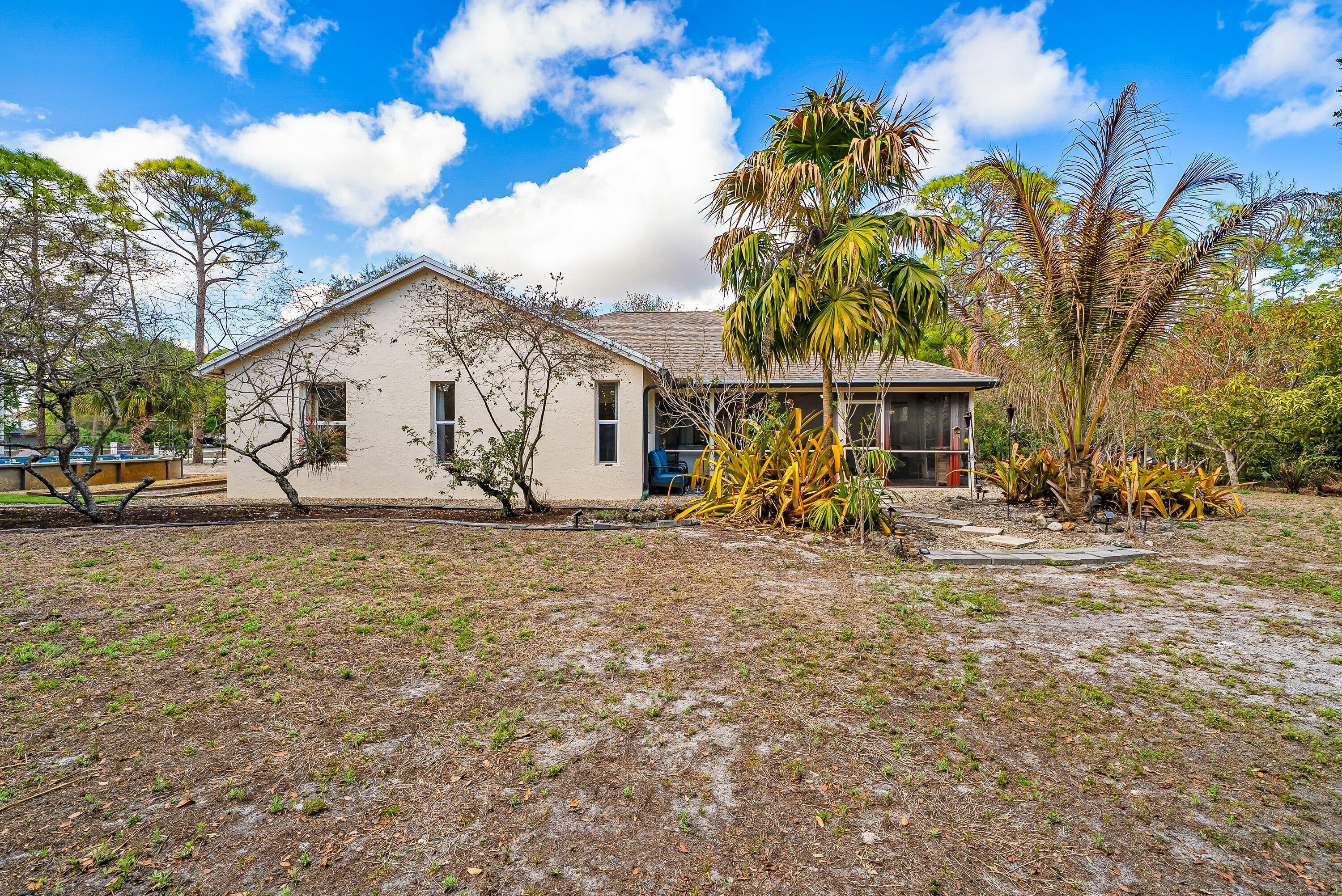 18098 93rd Road North The Acreage, FL 33470 - Photo 36 of 60 a view of a white house with a large tree and yard