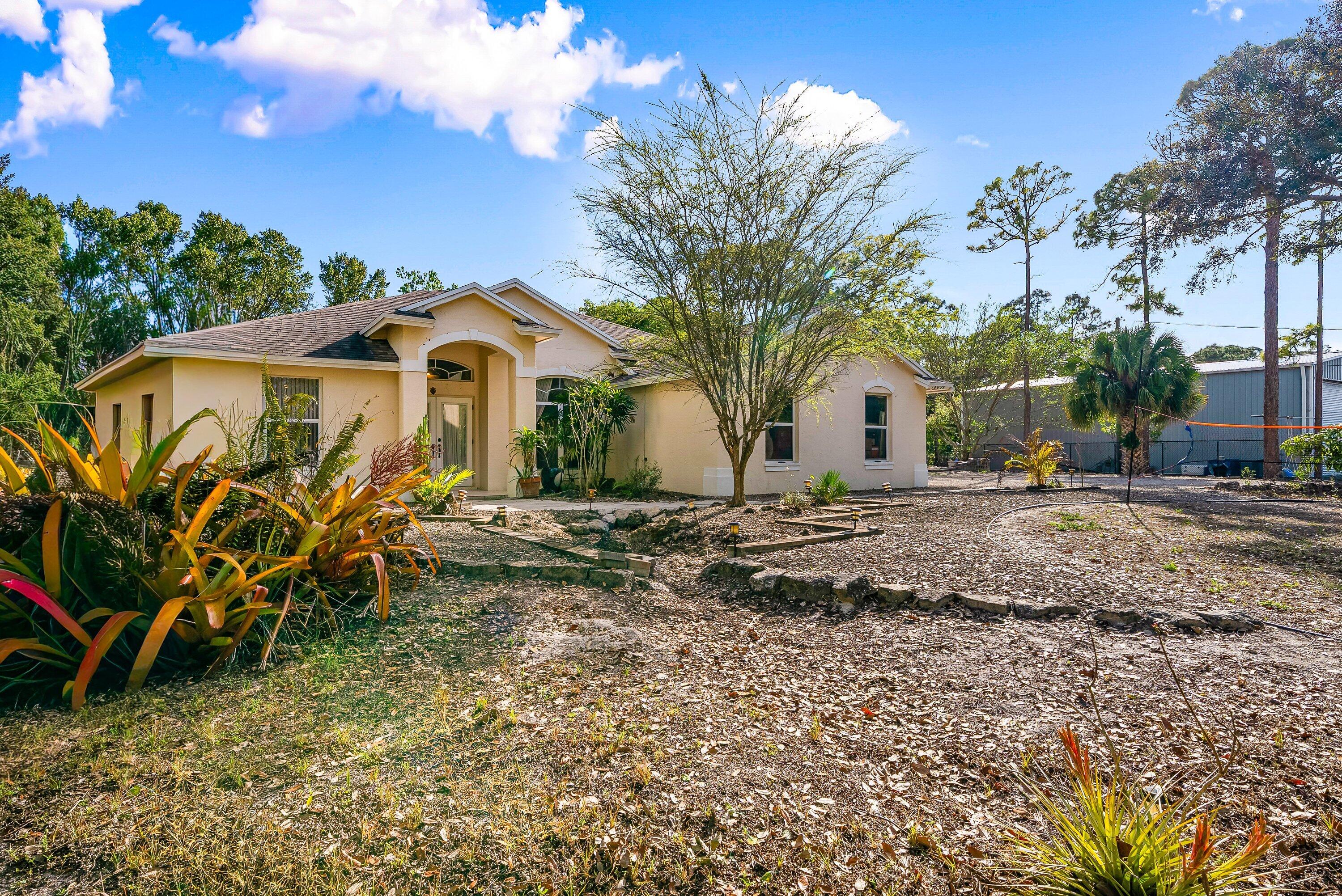 18098 93rd Road North The Acreage, FL 33470 - Photo 6 of 60 a front view of a house with garden