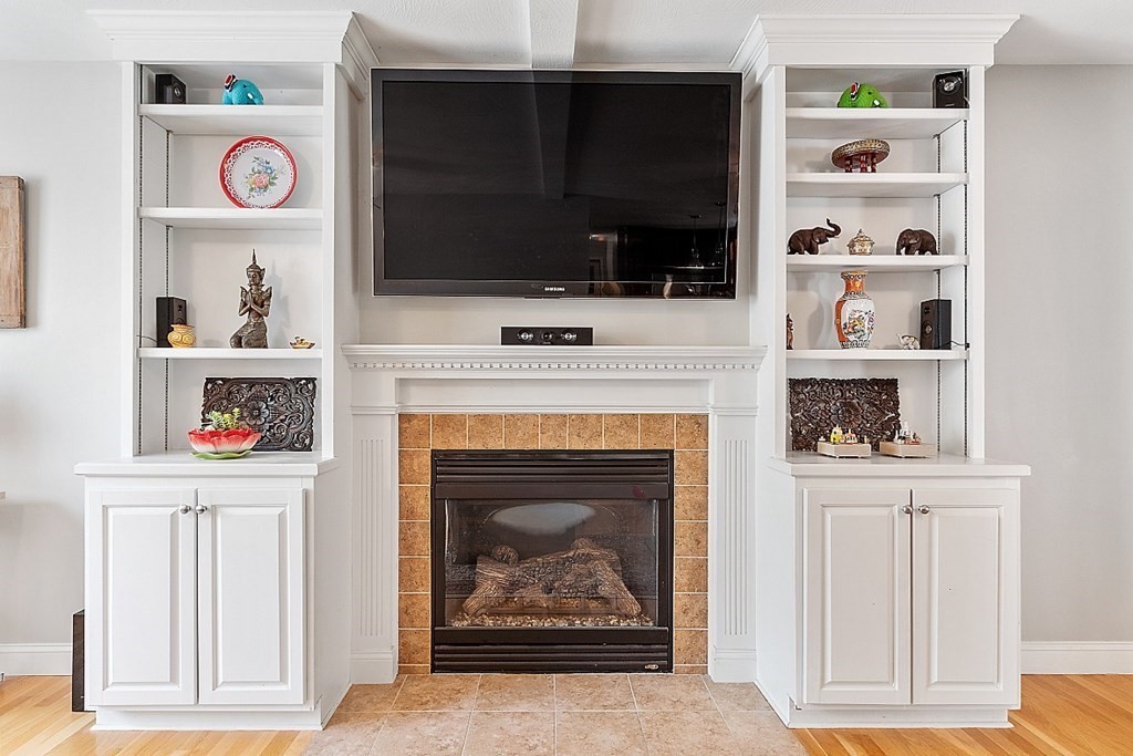 63 Manchester Street Nashua, NH 03064 - Photo 11 of 39 a living room with a fireplace a flat screen tv and a window