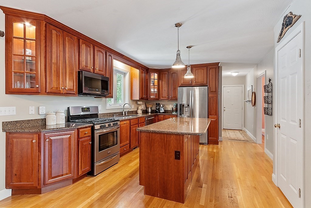 63 Manchester Street Nashua, NH 03064 - Photo 12 of 39 a kitchen with stainless steel appliances granite countertop a refrigerator a stove top oven a sink dishwasher and wooden cabinets with wooden floor