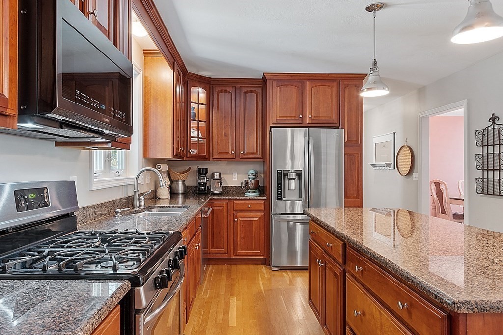 63 Manchester Street Nashua, NH 03064 - Photo 14 of 39 a kitchen with stainless steel appliances granite countertop a stove a sink dishwasher a refrigerator and wooden cabinets with wooden floor