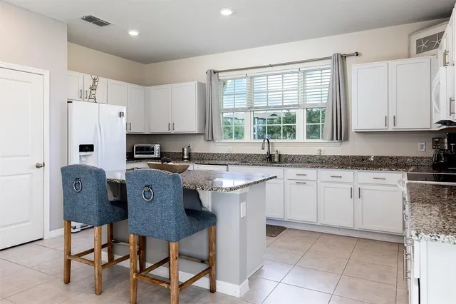 a kitchen with stainless steel appliances kitchen island granite countertop a dining table chairs and white cabinets
